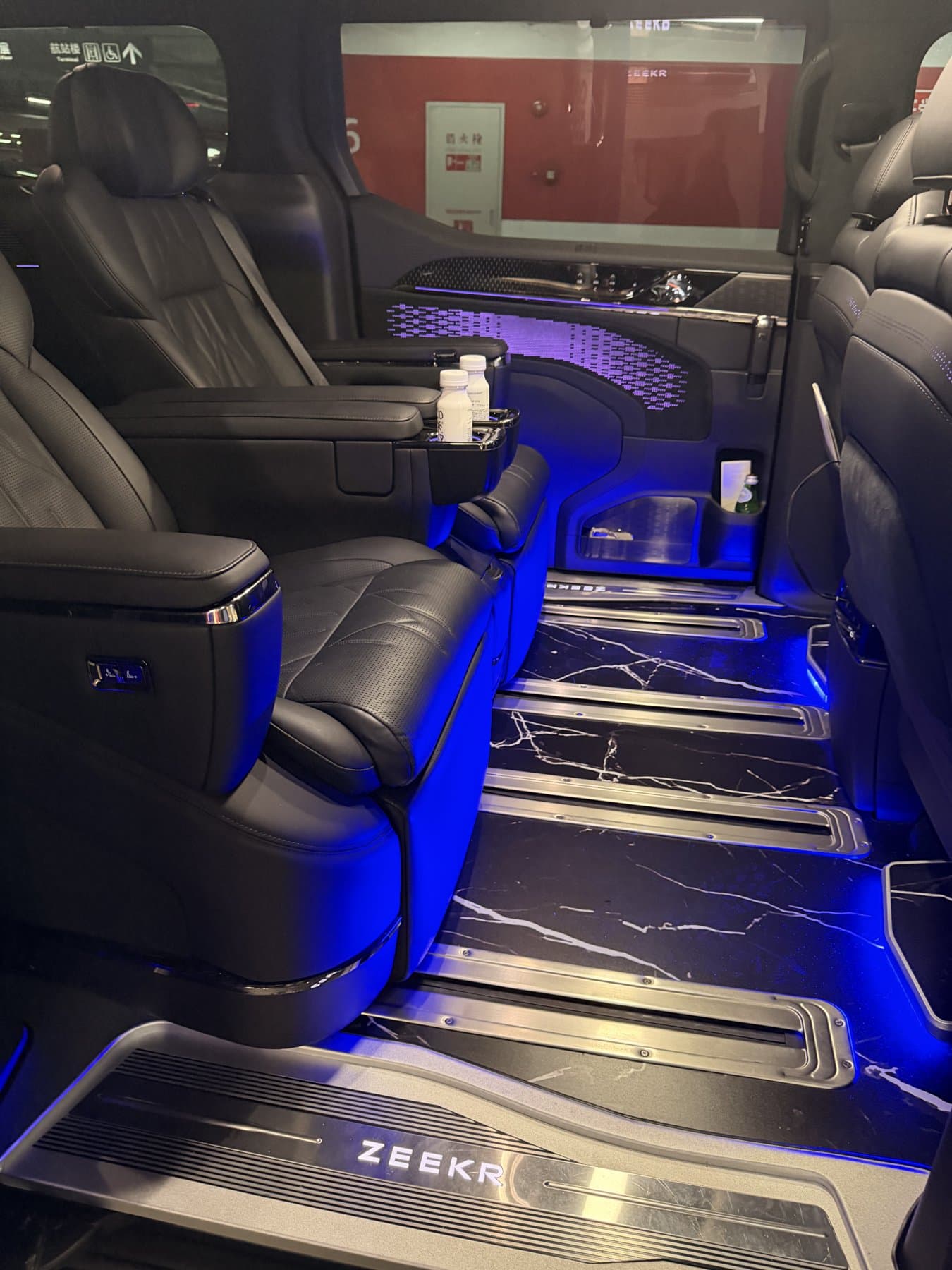 Rear cabin of a Zeekr 009 with two captain's chairs lit by blue floor lighting